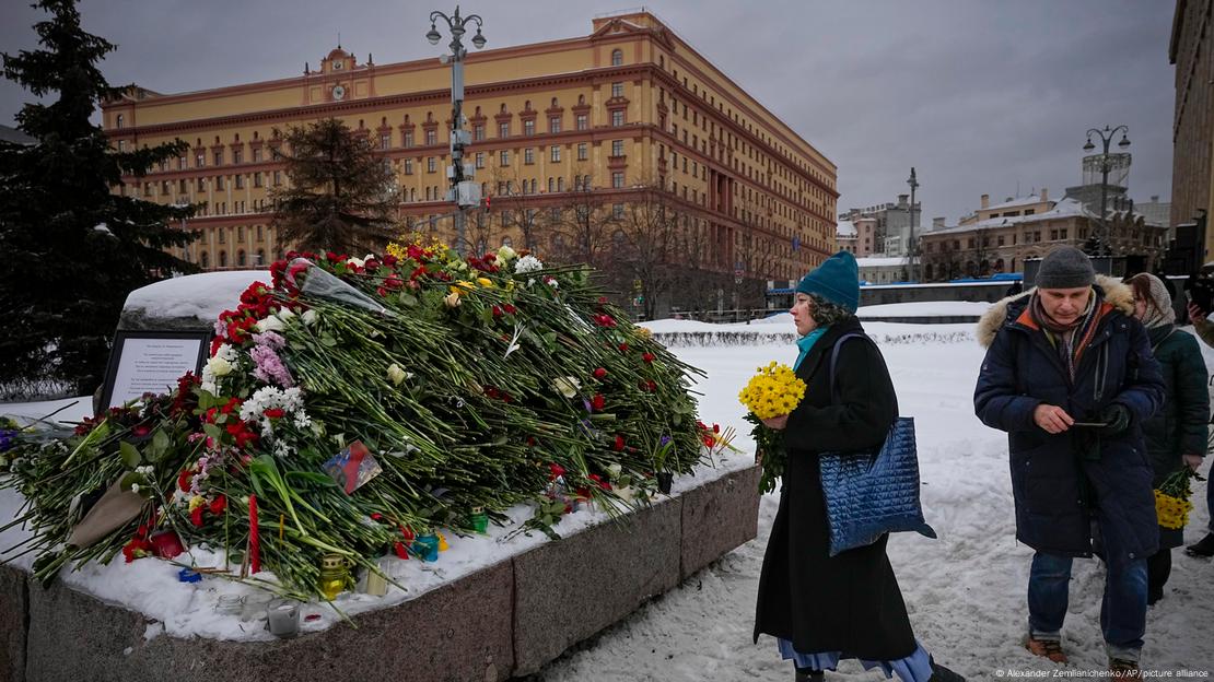 Un grupo de personas deposita flores en Moscú para rendir el último homenaje a Alexei Navalny en una gran roca de las islas Solovetsky, donde se estableció el primer campo del sistema de prisiones políticas Gulag, con el edificio histórico del Servicio Federal de Seguridad (FSB, sucesor del KGB soviético) al fondo. (Archivo: 17.02.2024)